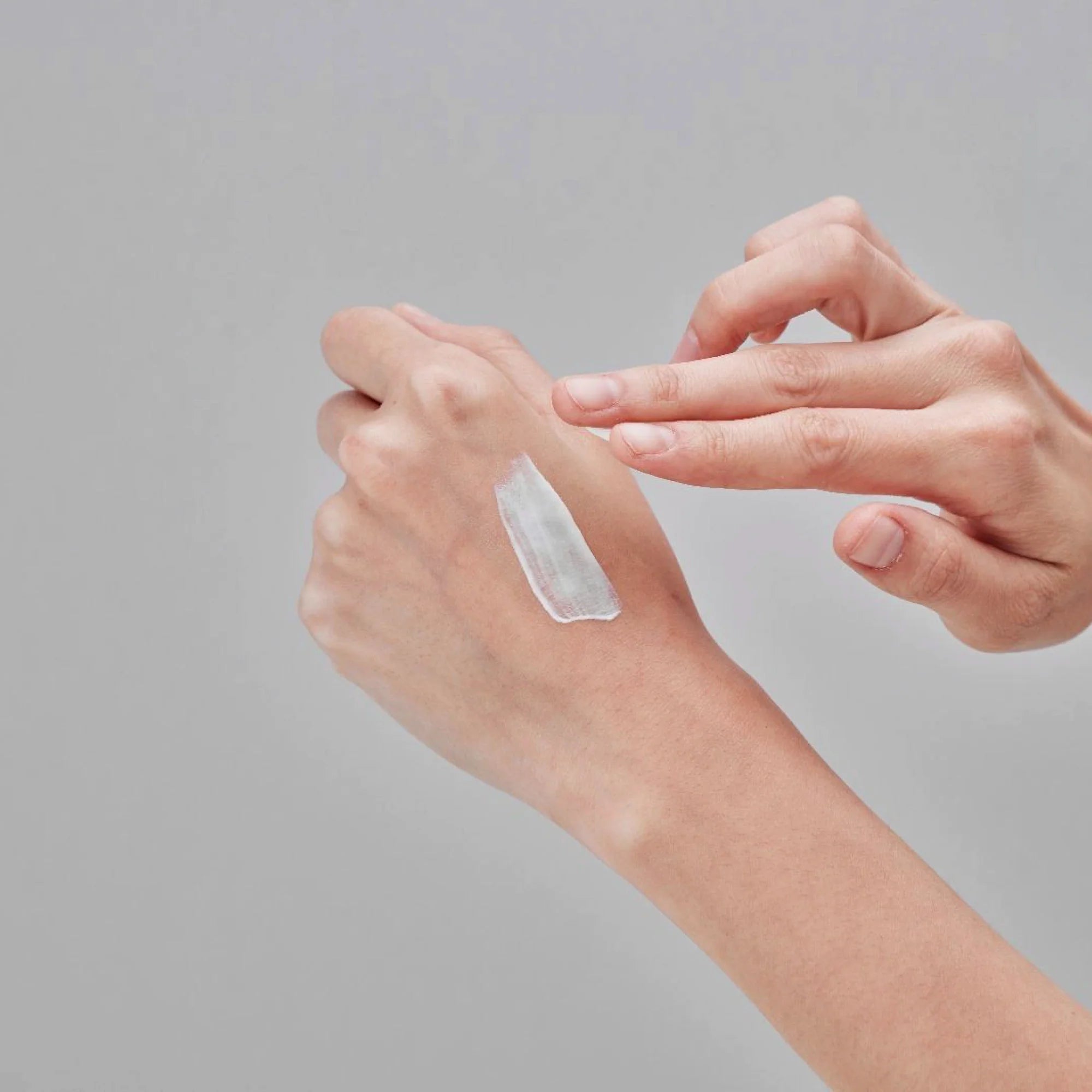 Glutanex Glow Sun Cream Light bottle – brightening and cooling Korean facial sunscreen SPF 50+ PA++++ with 50,000 ppm liposomal glutathione to brighten dark spots, provide a natural glow, and offer comprehensive UV protection, shown with a small swatch of its lightweight, non-greasy texture on the hand.