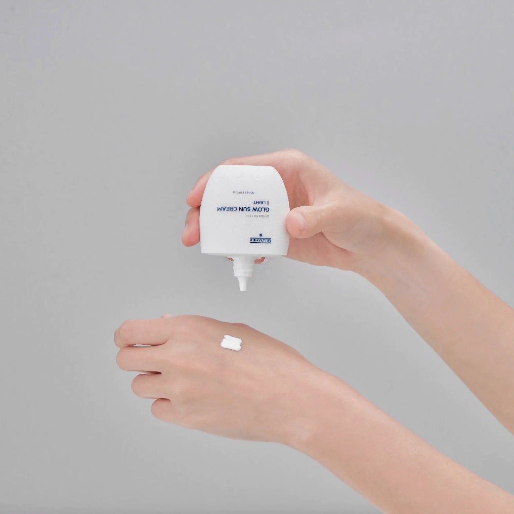 Glutanex Glow Sun Cream Light bottle – brightening and cooling Korean facial sunscreen SPF 50+ PA++++ with 50,000 ppm liposomal glutathione to brighten dark spots, provide a natural glow, and offer comprehensive UV protection, shown with a small swatch of its lightweight, non-greasy texture on the hand.